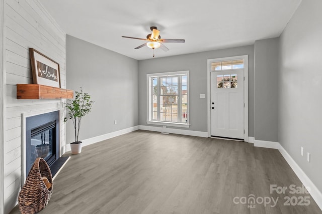 unfurnished living room with hardwood / wood-style flooring, a large fireplace, and ceiling fan