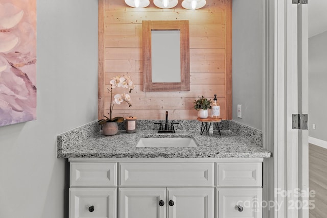 bathroom with vanity, wooden walls, and wood-type flooring