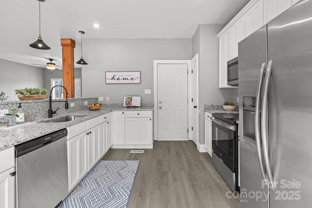 kitchen with pendant lighting, sink, stainless steel appliances, and white cabinets