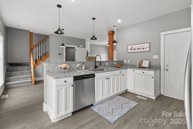 kitchen featuring pendant lighting, dishwasher, sink, white cabinets, and kitchen peninsula