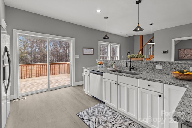 kitchen with sink, white cabinetry, light stone counters, dishwasher, and pendant lighting