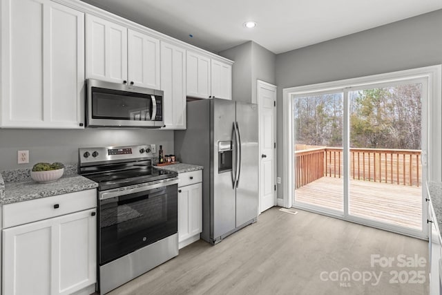 kitchen featuring light stone counters, appliances with stainless steel finishes, light wood-type flooring, and white cabinets