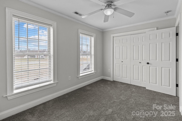 unfurnished bedroom featuring crown molding, ceiling fan, dark carpet, and a closet