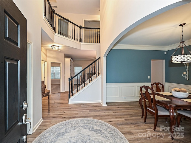 foyer entrance with crown molding, a towering ceiling, and hardwood / wood-style floors