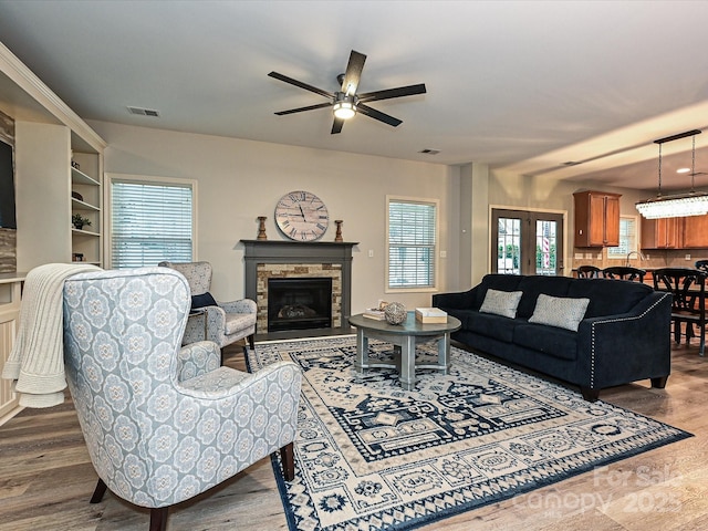 living room with wood-type flooring, ceiling fan, and a fireplace