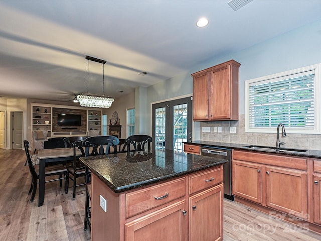 kitchen with sink, hanging light fixtures, light hardwood / wood-style flooring, dishwasher, and a kitchen island