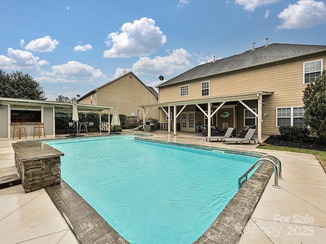 view of swimming pool with a patio and an outdoor bar