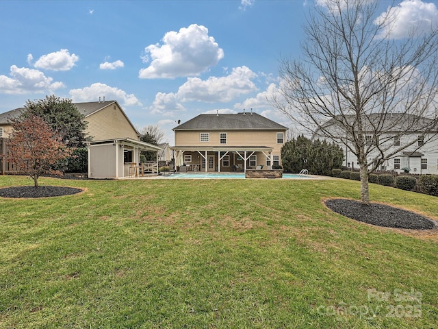 rear view of property featuring an outbuilding, a lawn, and a patio