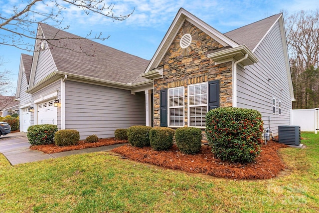 view of front of property with a garage, a front lawn, and central air condition unit