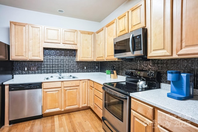 kitchen featuring sink, decorative backsplash, light wood-type flooring, and appliances with stainless steel finishes