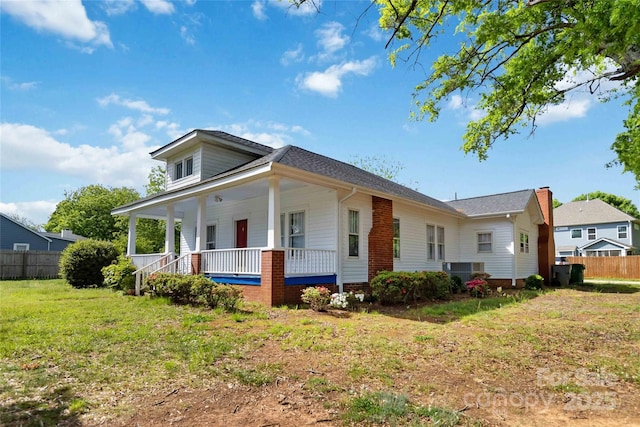 view of front facade featuring central air condition unit, covered porch, fence, and a front lawn