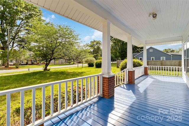 wooden terrace featuring a porch and a lawn