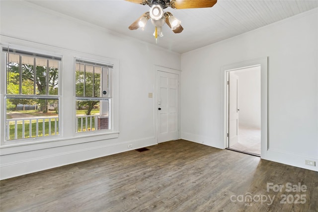 empty room with ceiling fan, wood finished floors, baseboards, and ornamental molding