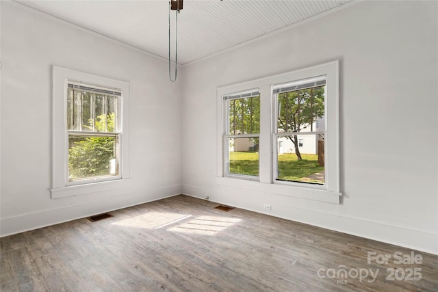 unfurnished room with baseboards, visible vents, and wood finished floors