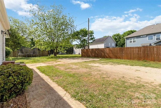 view of yard featuring a trampoline and fence