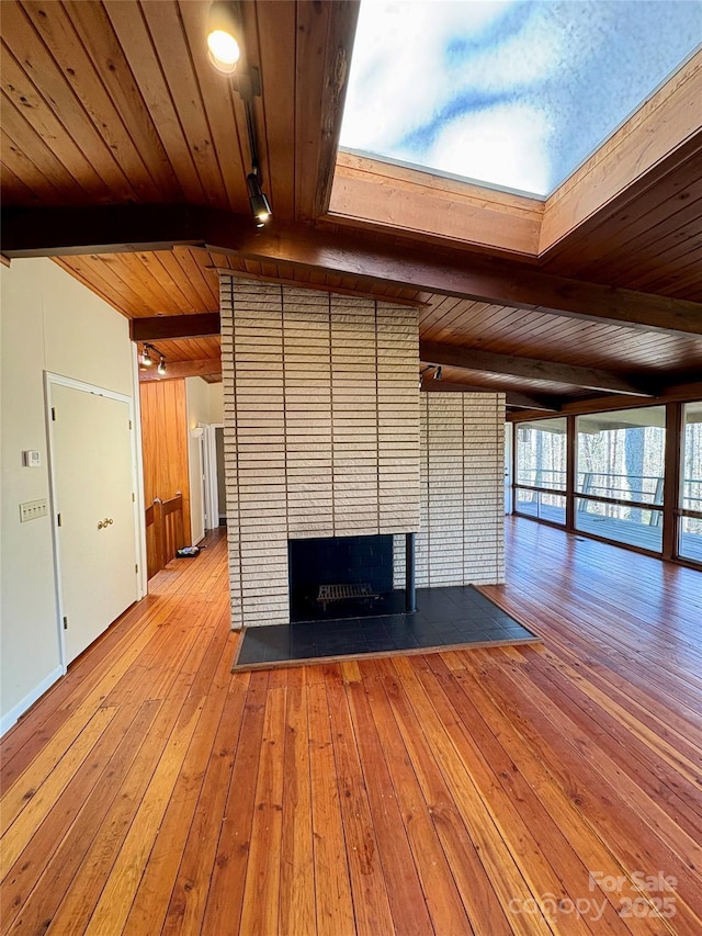 unfurnished living room featuring a brick fireplace, wooden ceiling, vaulted ceiling with beams, and light wood-type flooring