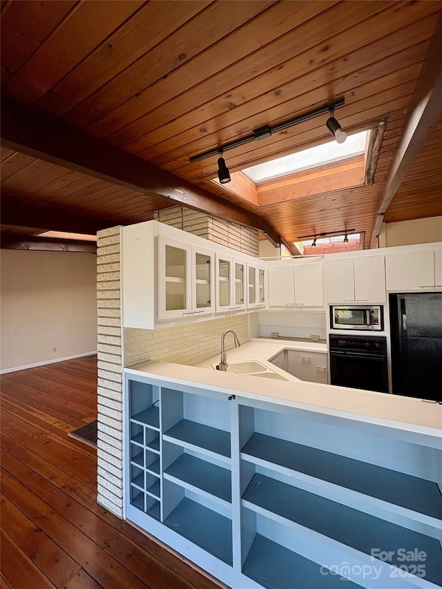 kitchen featuring a skylight, sink, white cabinets, and black appliances