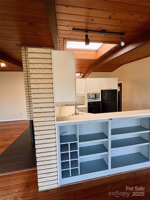 kitchen featuring sink, white cabinetry, wood-type flooring, beam ceiling, and black appliances