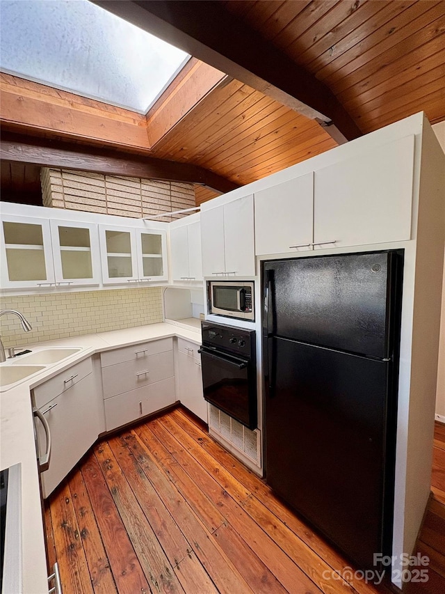 kitchen featuring sink, tasteful backsplash, black appliances, beamed ceiling, and white cabinets