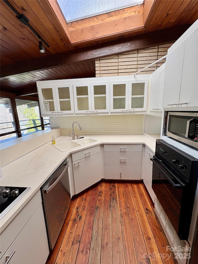 kitchen with white cabinetry, sink, a skylight, and black appliances