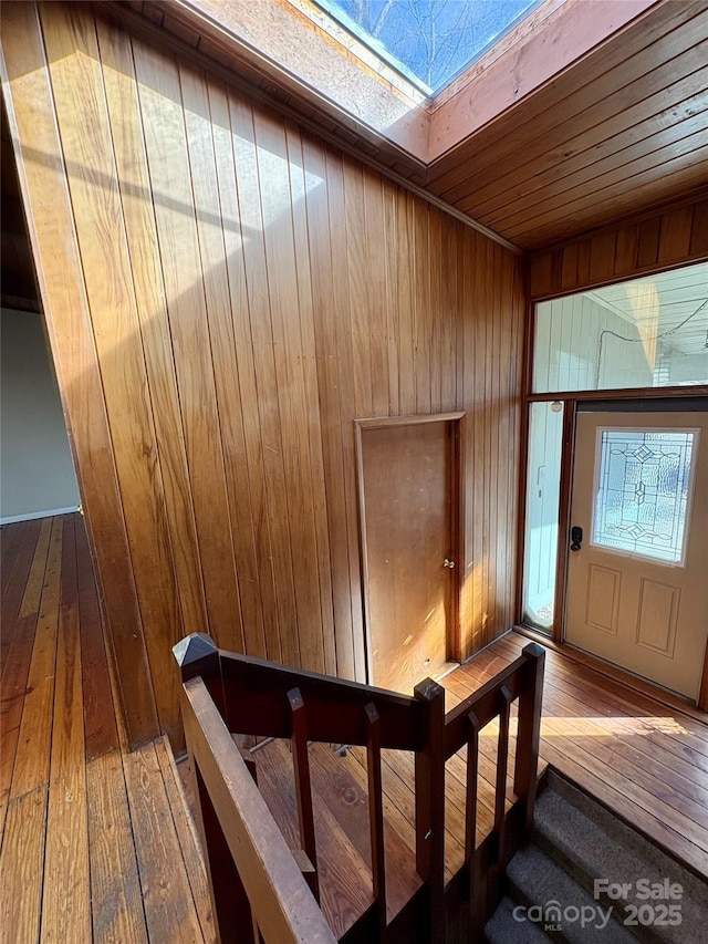 interior space featuring hardwood / wood-style flooring, wooden walls, and a skylight