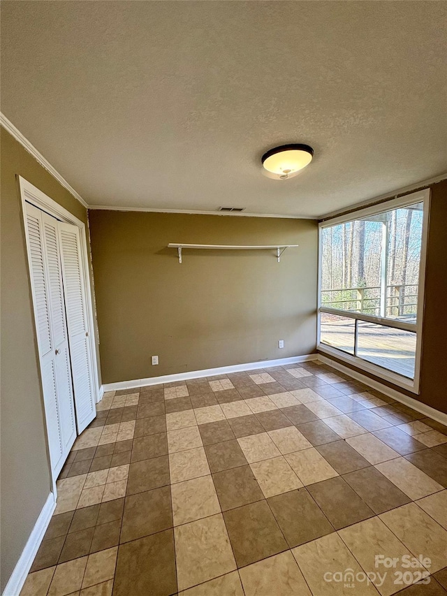 tiled spare room featuring crown molding and a textured ceiling