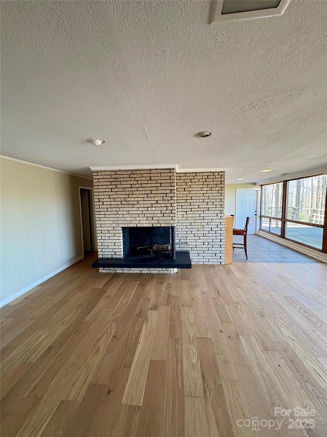 unfurnished living room featuring a brick fireplace, light hardwood / wood-style flooring, and a textured ceiling