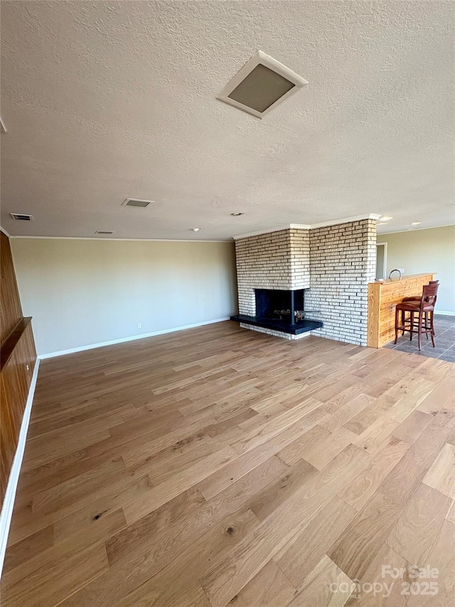 unfurnished living room with a fireplace, hardwood / wood-style floors, and a textured ceiling