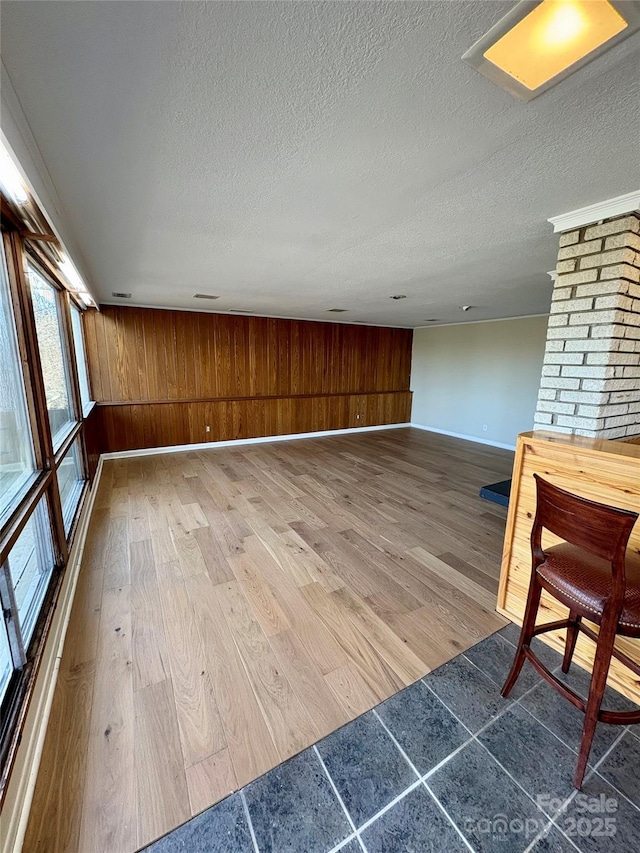 unfurnished room featuring hardwood / wood-style flooring, wooden walls, and a textured ceiling