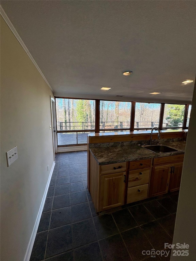 kitchen featuring crown molding, dark tile patterned flooring, sink, and dark stone countertops