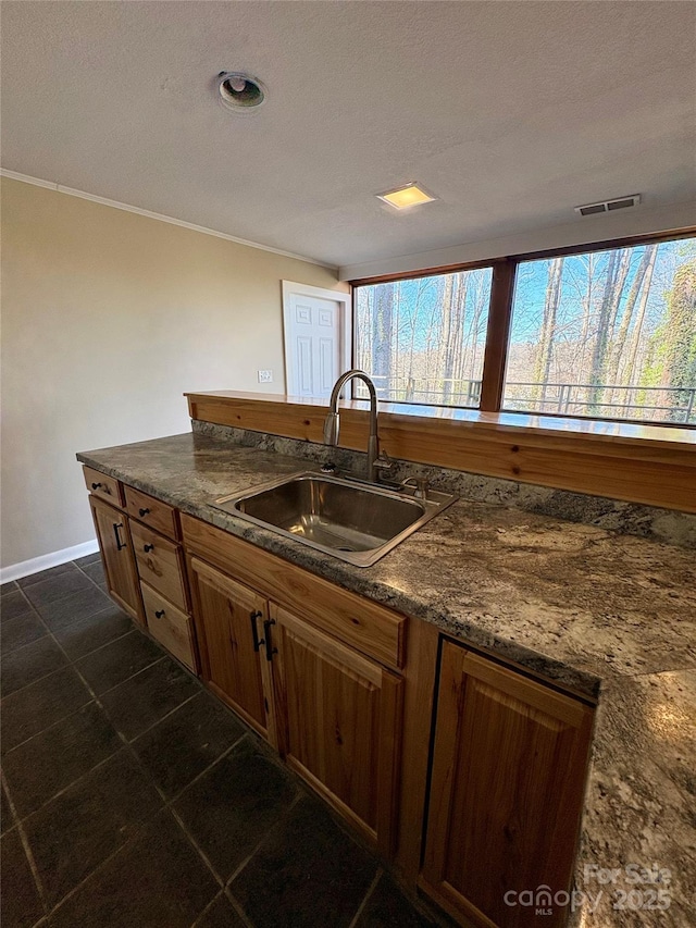 kitchen with dark tile patterned floors, ornamental molding, sink, and a textured ceiling