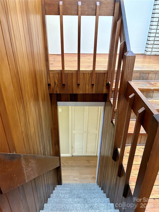 stairs featuring wooden walls and wood-type flooring