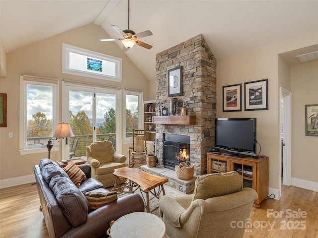 living room featuring ceiling fan, high vaulted ceiling, a fireplace, and light wood-type flooring