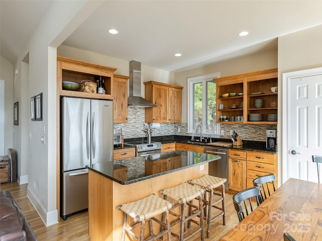 kitchen with a kitchen island, appliances with stainless steel finishes, sink, backsplash, and wall chimney range hood