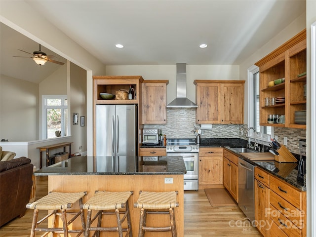 kitchen with wall chimney range hood, sink, backsplash, stainless steel appliances, and a center island