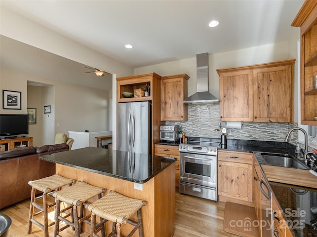 kitchen with a kitchen island, appliances with stainless steel finishes, tasteful backsplash, sink, and wall chimney exhaust hood