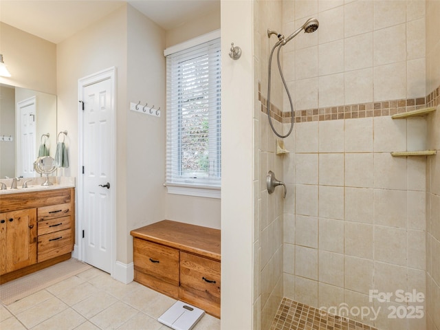 bathroom with tile patterned flooring, vanity, tiled shower, and a wealth of natural light