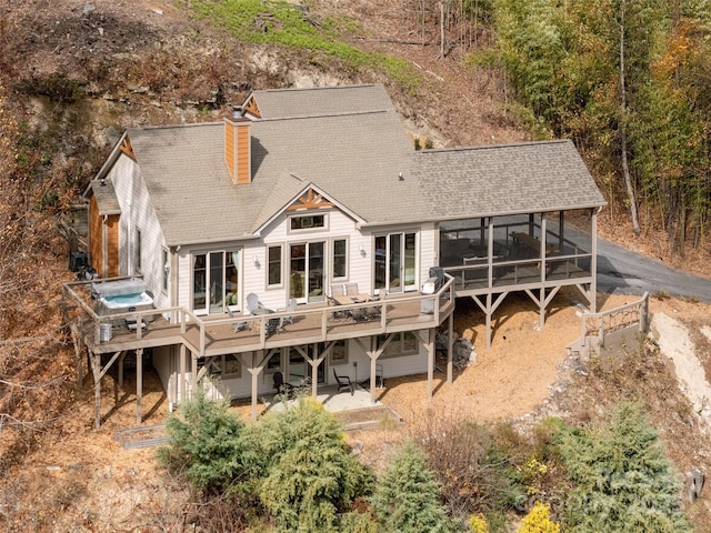 rear view of property featuring a jacuzzi, a deck, and a sunroom