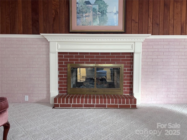 room details with a brick fireplace, wood walls, and carpet