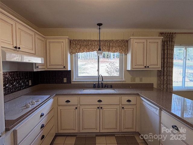 kitchen with a wealth of natural light, sink, ornamental molding, cream cabinets, and white appliances