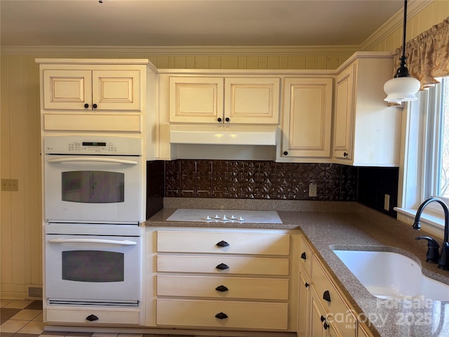 kitchen with a wealth of natural light, sink, hanging light fixtures, crown molding, and white appliances