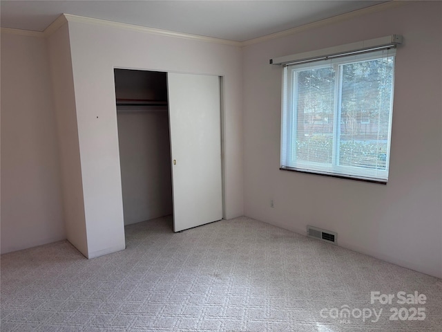 unfurnished bedroom with ornamental molding, light colored carpet, and a closet