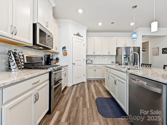 kitchen with sink, appliances with stainless steel finishes, pendant lighting, light stone countertops, and white cabinets