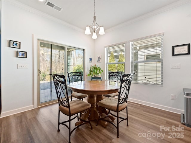 dining area featuring dark hardwood / wood-style flooring, crown molding, and a chandelier