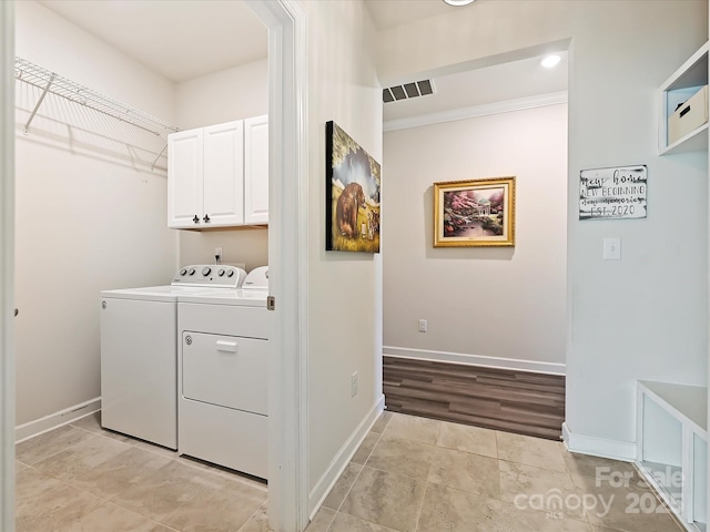 laundry area featuring light tile patterned floors, cabinets, and washing machine and clothes dryer