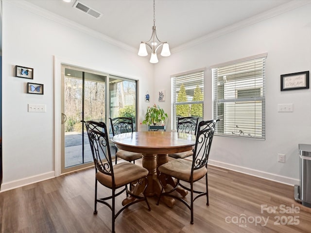 dining room featuring visible vents, crown molding, baseboards, dark wood finished floors, and an inviting chandelier