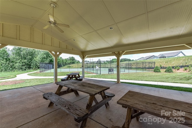 view of patio with a tennis court, ceiling fan, and fence
