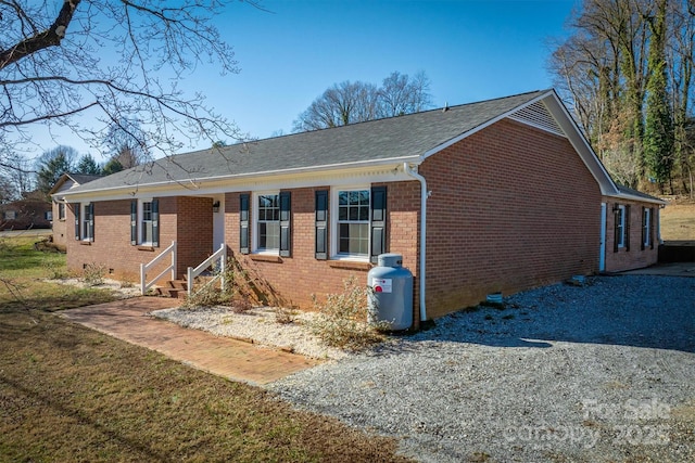 view of front of house with crawl space, brick siding, and gravel driveway