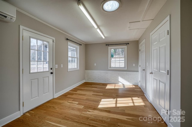 doorway featuring brick wall, a wall mounted air conditioner, light hardwood / wood-style flooring, and ornamental molding