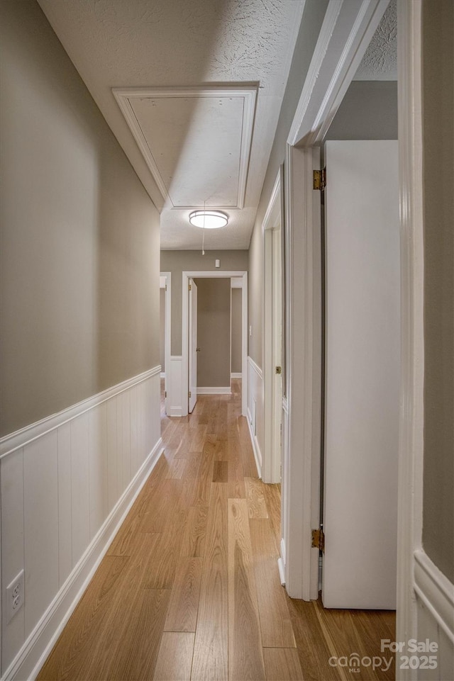 hall featuring a textured ceiling and light hardwood / wood-style flooring